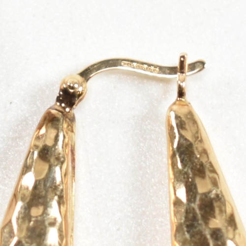 335 - A pair of hallmarked 9ct gold hammered hoop earrings. The arrow-shape hoop earrings having an all-ov... 