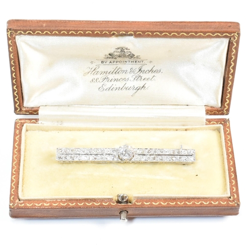 34 - An Edwardian platinum and diamond bar brooch pin. The brooch set with a central old cut diamond flan... 