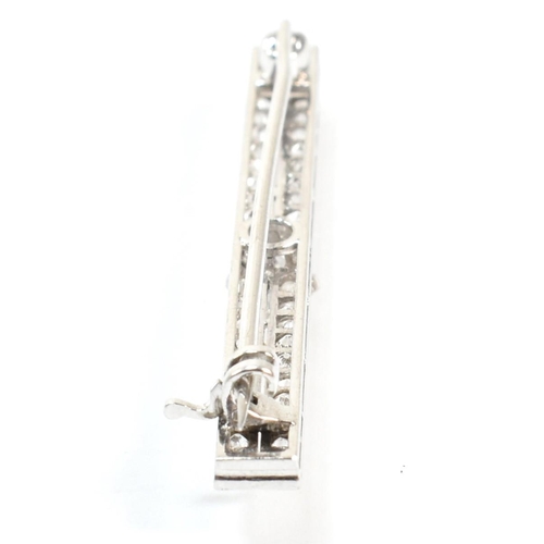 34 - An Edwardian platinum and diamond bar brooch pin. The brooch set with a central old cut diamond flan... 