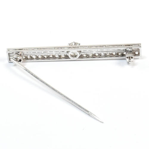 34 - An Edwardian platinum and diamond bar brooch pin. The brooch set with a central old cut diamond flan... 