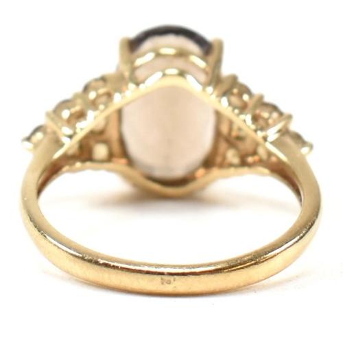 344 - A hallmarked 9ct gold and smoky quartz ring. The ring having a central four claw set oval cut smoky ... 