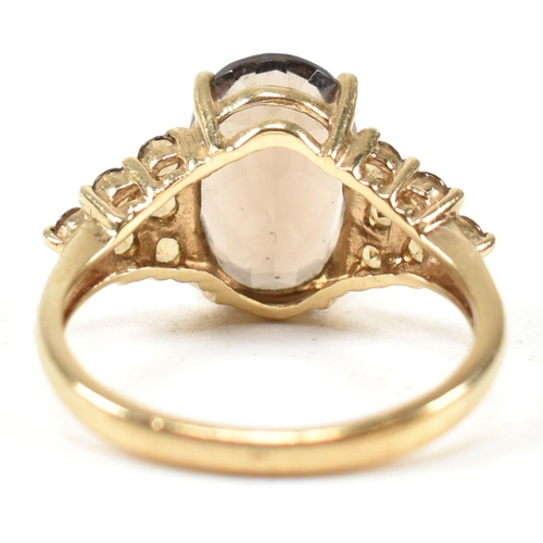 344 - A hallmarked 9ct gold and smoky quartz ring. The ring having a central four claw set oval cut smoky ... 