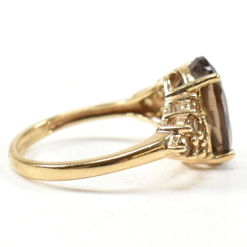 344 - A hallmarked 9ct gold and smoky quartz ring. The ring having a central four claw set oval cut smoky ... 