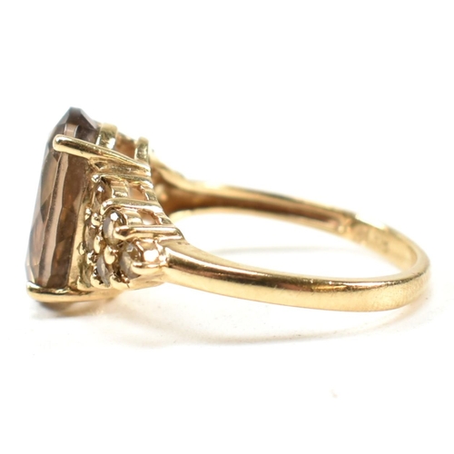 344 - A hallmarked 9ct gold and smoky quartz ring. The ring having a central four claw set oval cut smoky ... 