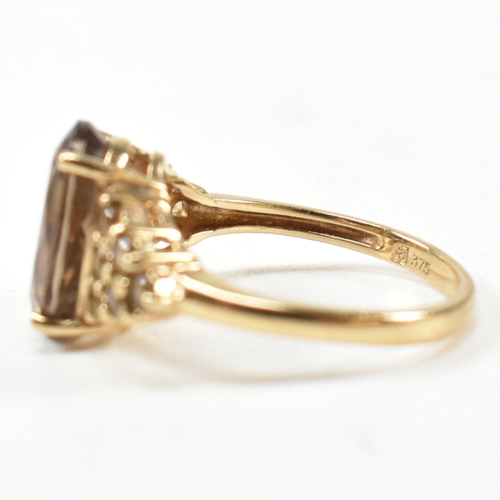 344 - A hallmarked 9ct gold and smoky quartz ring. The ring having a central four claw set oval cut smoky ... 