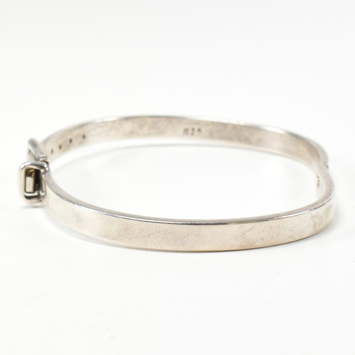 395 - A hallmarked silver belt buckle hinged bangle. The silver belt bangle having a central belt buckle c... 