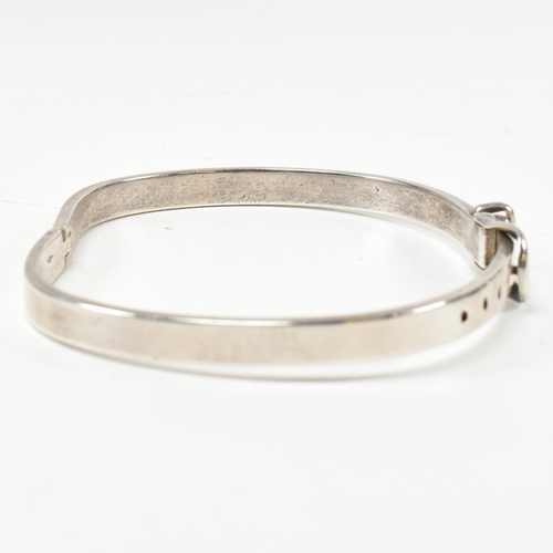 395 - A hallmarked silver belt buckle hinged bangle. The silver belt bangle having a central belt buckle c... 