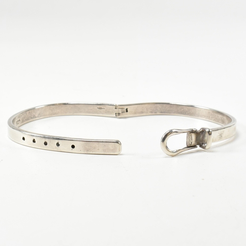 395 - A hallmarked silver belt buckle hinged bangle. The silver belt bangle having a central belt buckle c... 