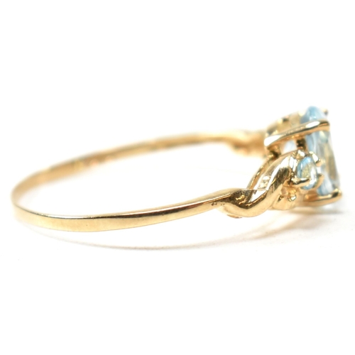 400 - A 9ct gold and blue topaz ring. The ring set with a central oval cut topaz flanked by two round cut ... 