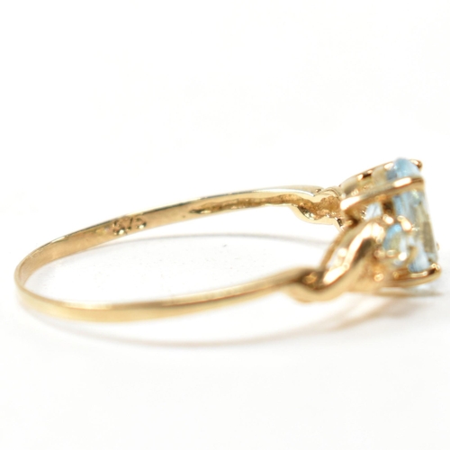 400 - A 9ct gold and blue topaz ring. The ring set with a central oval cut topaz flanked by two round cut ... 