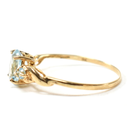 400 - A 9ct gold and blue topaz ring. The ring set with a central oval cut topaz flanked by two round cut ... 