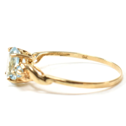 400 - A 9ct gold and blue topaz ring. The ring set with a central oval cut topaz flanked by two round cut ... 