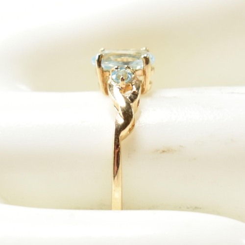 400 - A 9ct gold and blue topaz ring. The ring set with a central oval cut topaz flanked by two round cut ... 