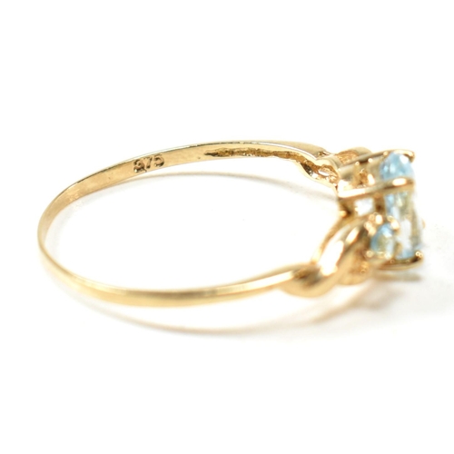 400 - A 9ct gold and blue topaz ring. The ring set with a central oval cut topaz flanked by two round cut ... 