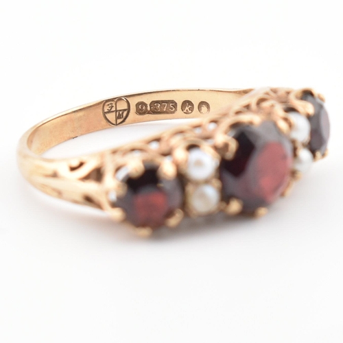 83 - A hallmarked 9ct gold, garnet and pearl three stone ring. The ring having three round mixed cut garn... 