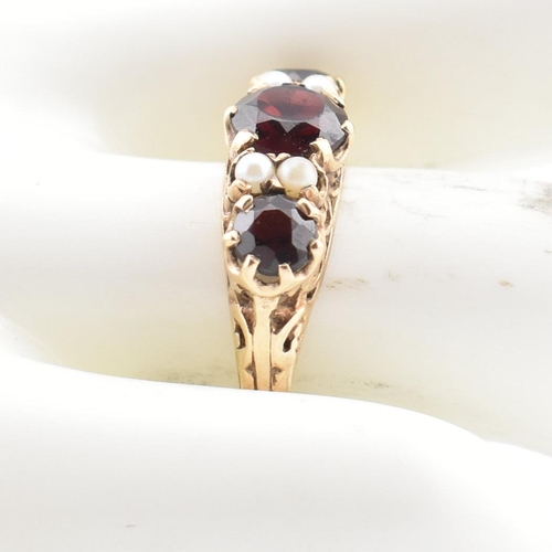 83 - A hallmarked 9ct gold, garnet and pearl three stone ring. The ring having three round mixed cut garn... 