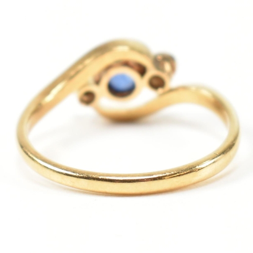 95 - An 18ct gold, diamond and sapphire crossover ring. The ring having a central bezel set round cut dia... 