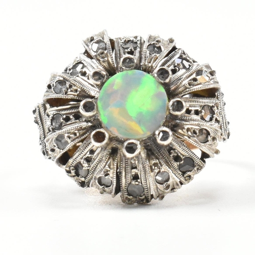 426 - A continental synthetic opal and diamond cluster ring. The ring having a domed cluster head set with... 