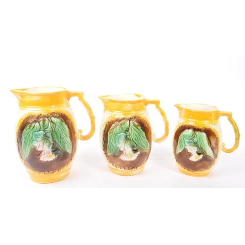 135 - A collection of three 19th Century Victorian ceramic graduating majolica  pitcher jugs George Jones ... 