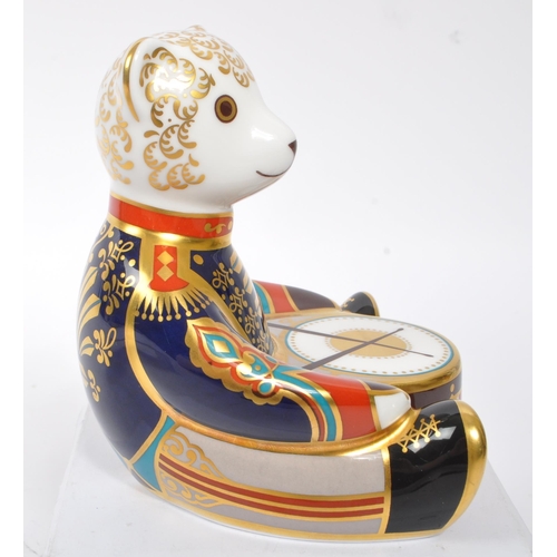 154 - Royal Crown Derby - A china porcelain ' Drummer Teddy ' paperweight in the form of a teddy bear sat ... 