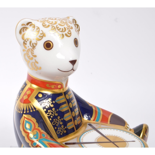 154 - Royal Crown Derby - A china porcelain ' Drummer Teddy ' paperweight in the form of a teddy bear sat ... 