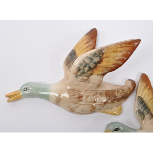 188 - A collection of three ceramic graduating wall hanging Beswick style figures in the form of birds / d... 