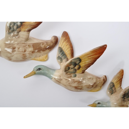 188 - A collection of three ceramic graduating wall hanging Beswick style figures in the form of birds / d... 