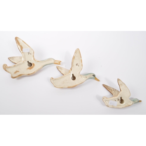 188 - A collection of three ceramic graduating wall hanging Beswick style figures in the form of birds / d... 