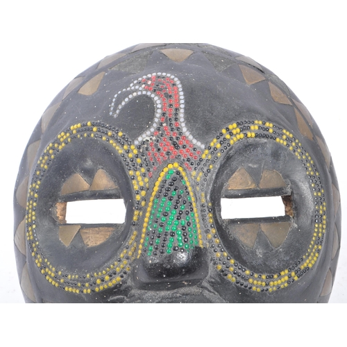 217 - A 20th century West African Ghanaian beaded ebonised wooden tribal mask. The mask of carved of round... 