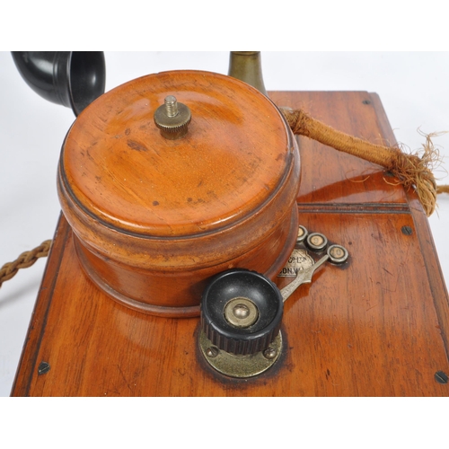 228 - An early 20th century candlestick upright telephone. With metal ring dial with receiver on a holder ... 