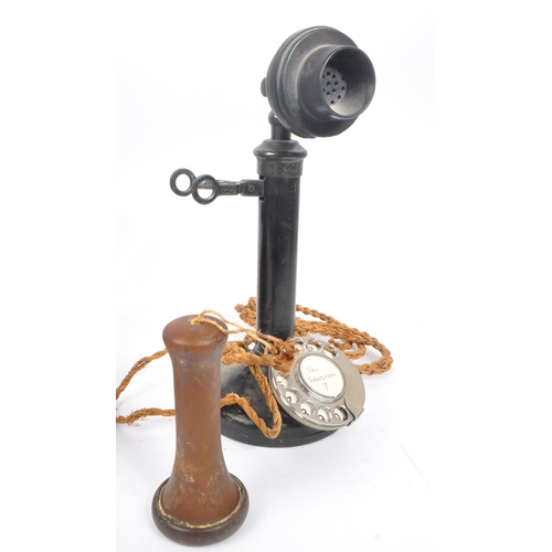 228 - An early 20th century candlestick upright telephone. With metal ring dial with receiver on a holder ... 