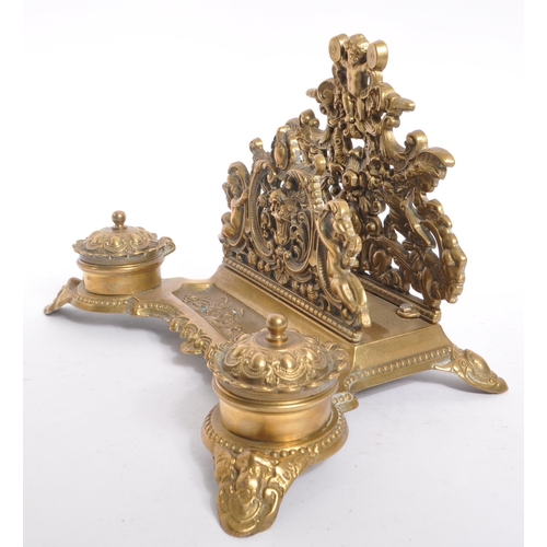 255 - A 20th century brass rococo manner inkwell desk tidy. The desk tidy raised on four feet, with matchi... 