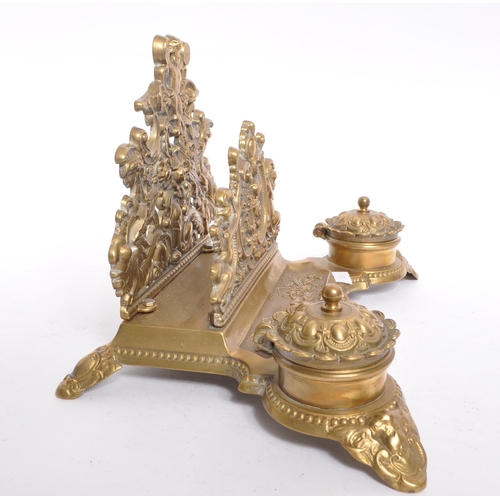 255 - A 20th century brass rococo manner inkwell desk tidy. The desk tidy raised on four feet, with matchi... 