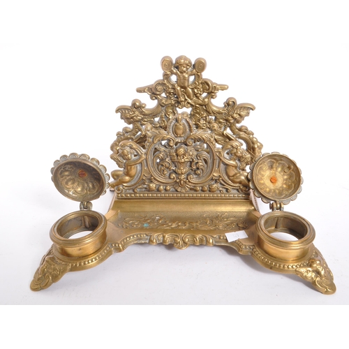 255 - A 20th century brass rococo manner inkwell desk tidy. The desk tidy raised on four feet, with matchi... 