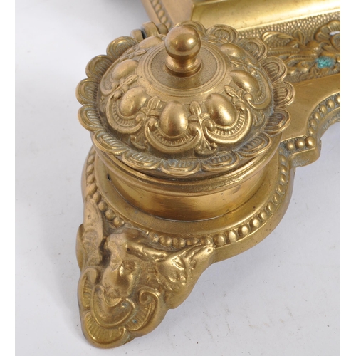 255 - A 20th century brass rococo manner inkwell desk tidy. The desk tidy raised on four feet, with matchi... 