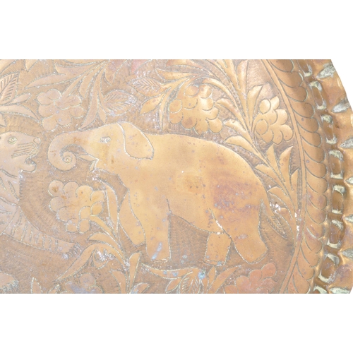 293 - An early 20th Century Indian brass engraved charger tray depicting a tiger and an elephant to the ce... 