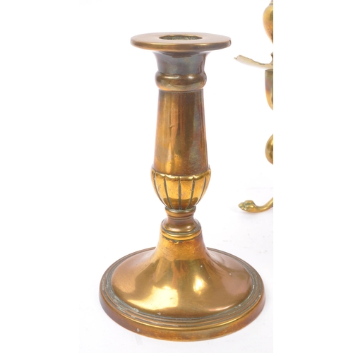 294 - A collection of four brass candlesticks comprising of a 19th Century pair in the form of crouching p... 