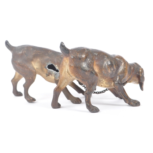 314 - A hollow bronze figurine in the form of two dogs / hounds attached together by chain, both standing ... 