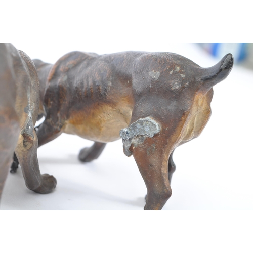 314 - A hollow bronze figurine in the form of two dogs / hounds attached together by chain, both standing ... 