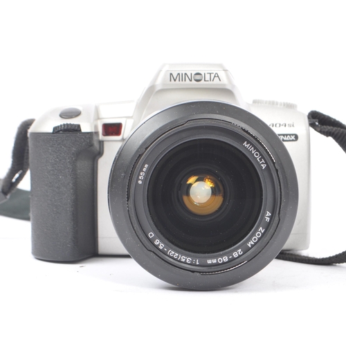 329 - Minolta - Two circa 1999 Minolta Dynax 404si 35mm SLR cameras. The cameras each in silver and black ... 