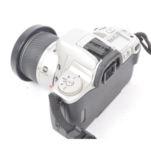 329 - Minolta - Two circa 1999 Minolta Dynax 404si 35mm SLR cameras. The cameras each in silver and black ... 