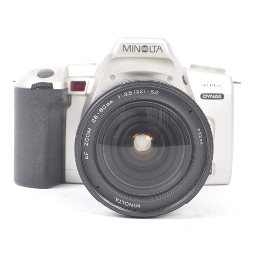 329 - Minolta - Two circa 1999 Minolta Dynax 404si 35mm SLR cameras. The cameras each in silver and black ... 