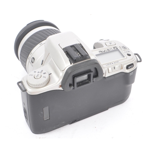 329 - Minolta - Two circa 1999 Minolta Dynax 404si 35mm SLR cameras. The cameras each in silver and black ... 