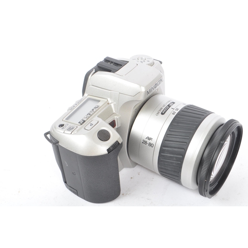 329 - Minolta - Two circa 1999 Minolta Dynax 404si 35mm SLR cameras. The cameras each in silver and black ... 