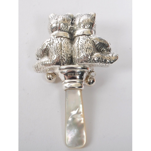 346 - A sterling silver babies rattle having mother of pearl style handle with figures of two bears finial... 