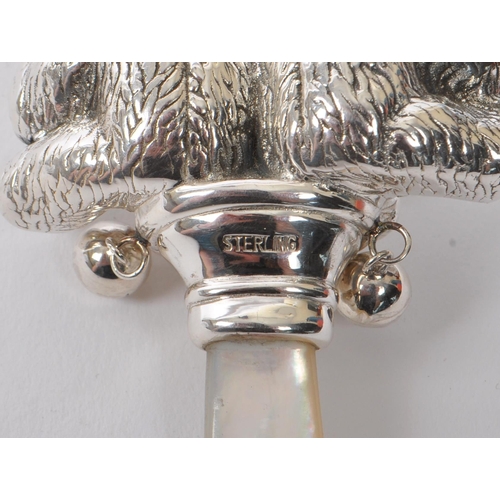 346 - A sterling silver babies rattle having mother of pearl style handle with figures of two bears finial... 