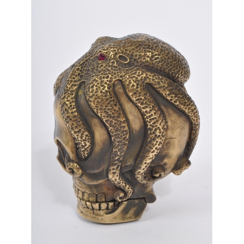 358 - A 20th Century brass vesta case in the form of a skull covered by an octopus with red stone eyes. En... 