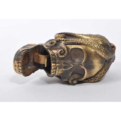 358 - A 20th Century brass vesta case in the form of a skull covered by an octopus with red stone eyes. En... 