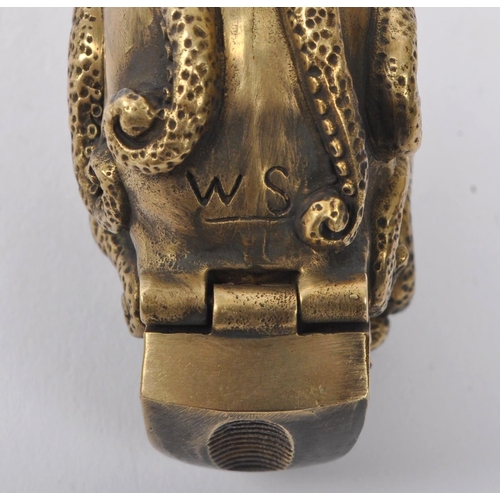 358 - A 20th Century brass vesta case in the form of a skull covered by an octopus with red stone eyes. En... 