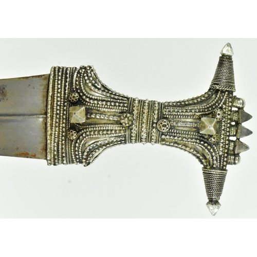 31 - An early 20th Century Saudi Arabian Jambiya / Khanjar dagger. Ornate hilt with applied silver orname... 